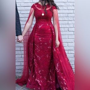 Red sequin tight dress with attached over skirt and flowing tulle cape sleeves.